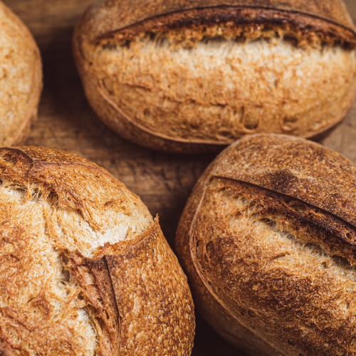 Close-up of four rustic bread loaves on a wooden surface